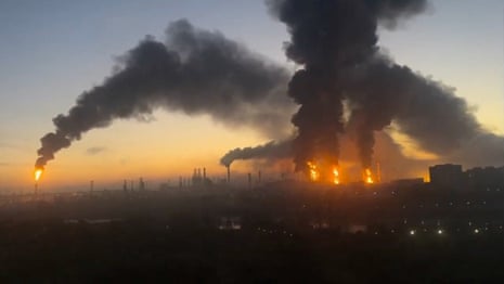 Thick black smoke billows over Moscow Oil Refinery, with flames visible at sunset